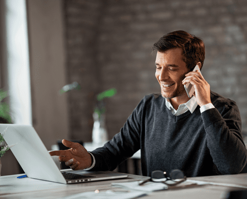 Male Real Estate Agent speaking to clients on the phone while sitting in a brick-walled room. Structur Residential Construction Consulting